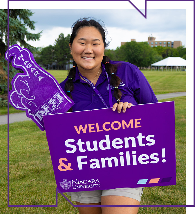 niagara university tour guide with foam finger and sign welcoming NU families