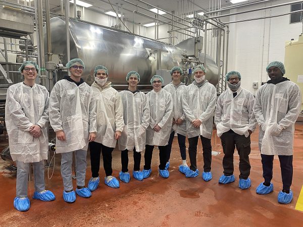Students standing in a factory with protective gear on