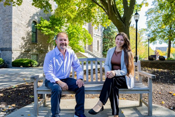 male and female transfer student on a bench outside of alumni hall