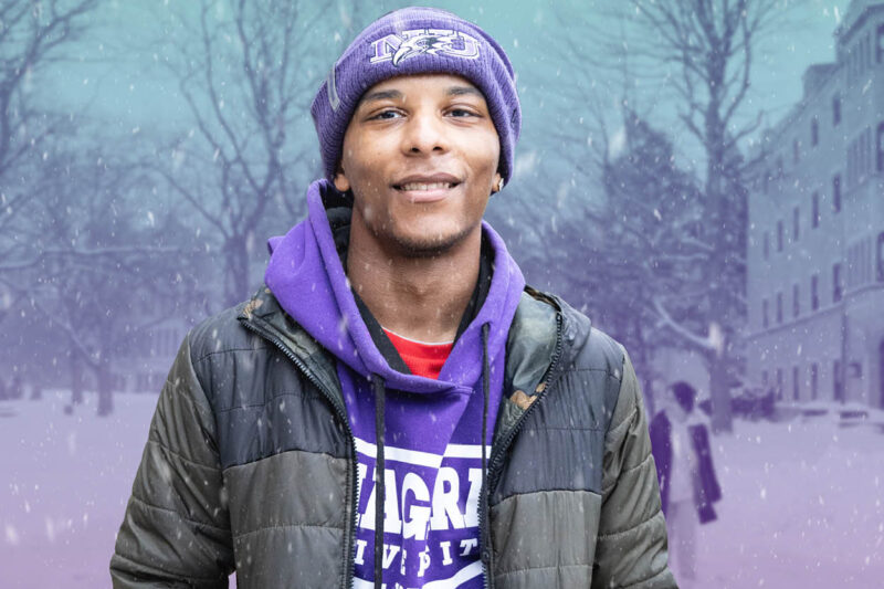Student dressed in NU attire stands in the snow at Winter Open House