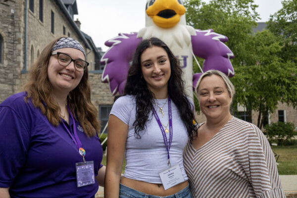Orientation Leader, student and mom standing in front of inflatable monte